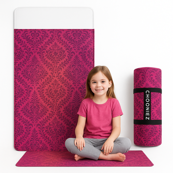 Child sitting on a pink patterned sleeping bag with a matching rolled-up mat and blanket in the background.